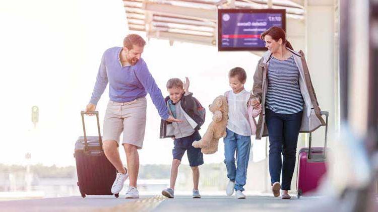 Mom, dad and two kids traveling in the airport with their baggage.